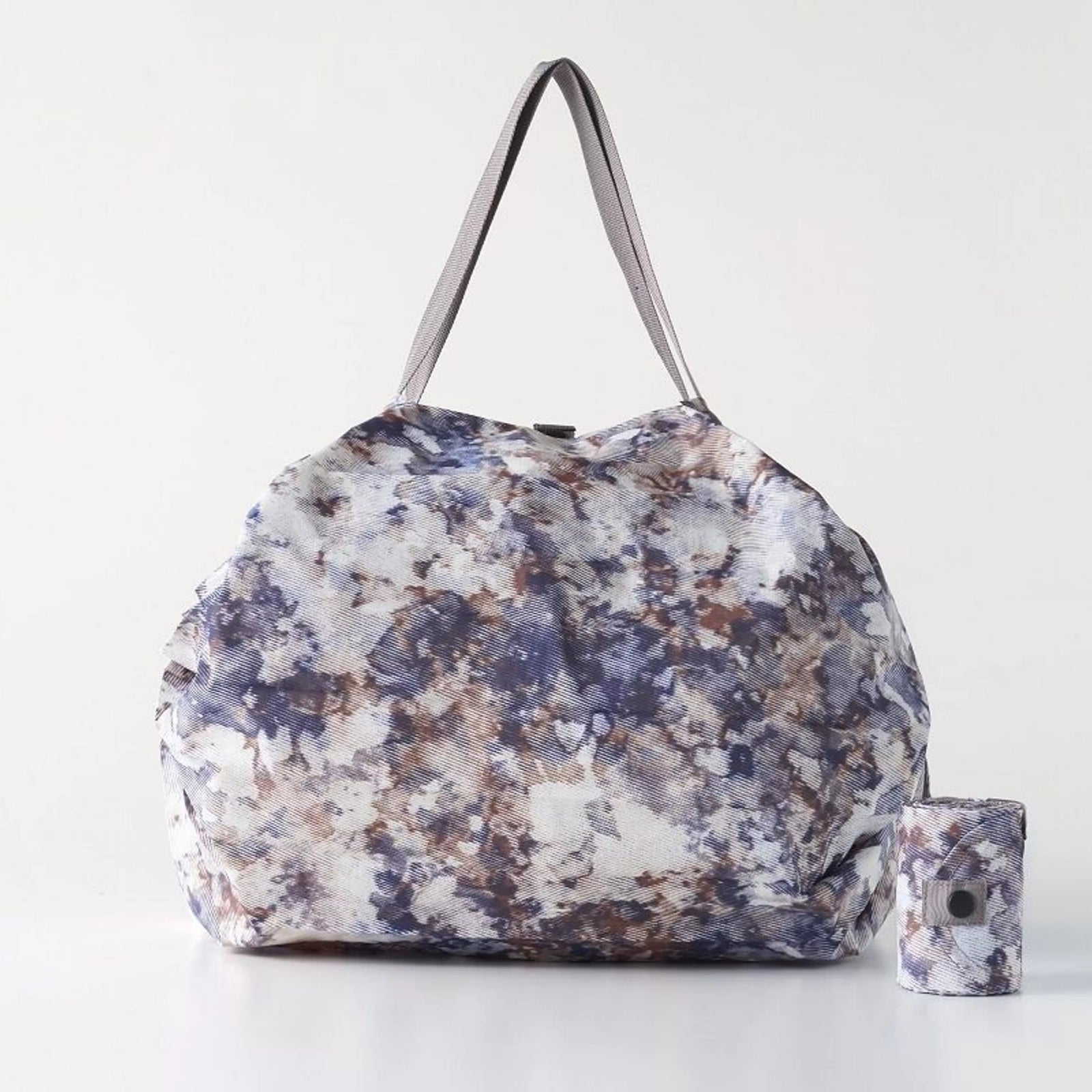 Woman holding a floral-patterned bag in a room with wooden walls and a counter.