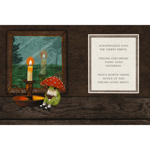A square art print or card featuring a dark wood background with a framed illustration of a frog in a red mushroom cap sitting beside a candle, next to a cream text panel that reads: 'ACKNOWLEDGE EVEN THE TINIEST SHIFTS. FEELING LESS DREAD TODAY THAN YESTERDAY.