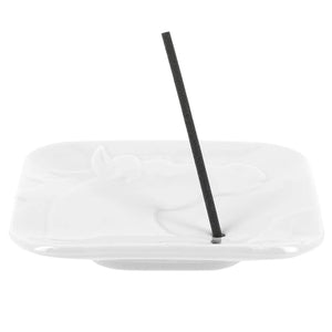 White oval dish with a black straw on a white background
