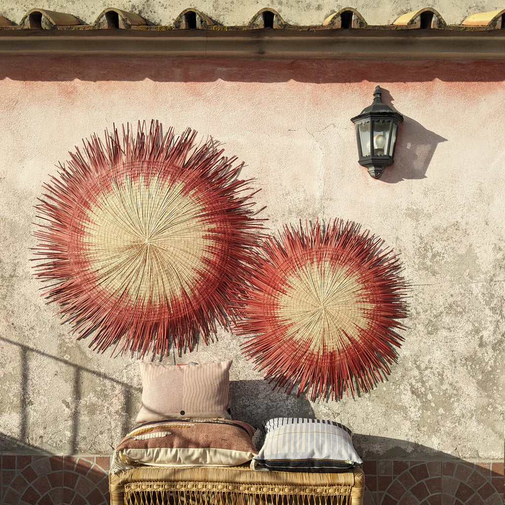 wall decor sun circles in red hang on wall outside on top of pillows and bench