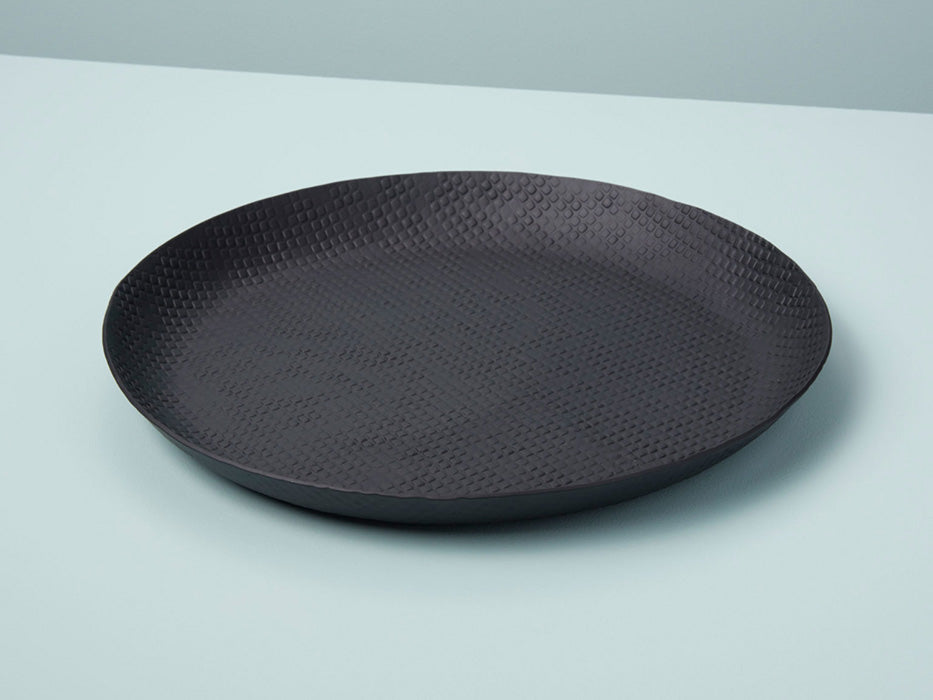 A round, black crosshatch patterned aluminum tray on a light background.