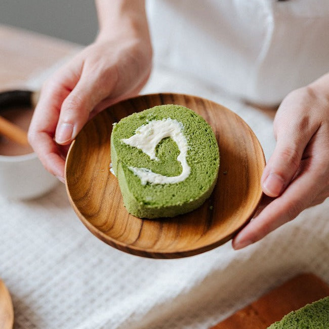 A wooden dessert plate with teak wood grain, containing some dried fruit pieces.