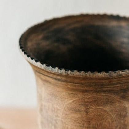 A handcrafted solid Mango Wood vase with a rustic finish, displayed against a soft-focus background.